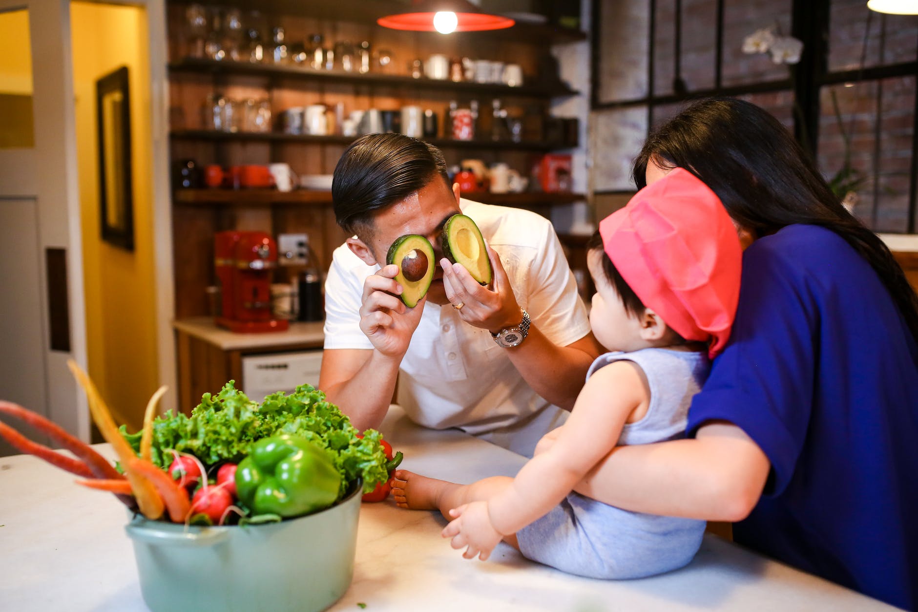 man covering his eyes ith avocado while playing with the baby