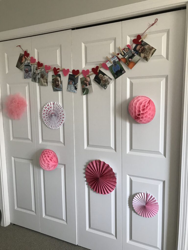 pink and white decorations with pictures hanging on a felt heart garland.