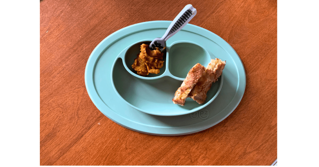 Sage plate with pumpkin butter, baby spoon and two slices of pancake in corner