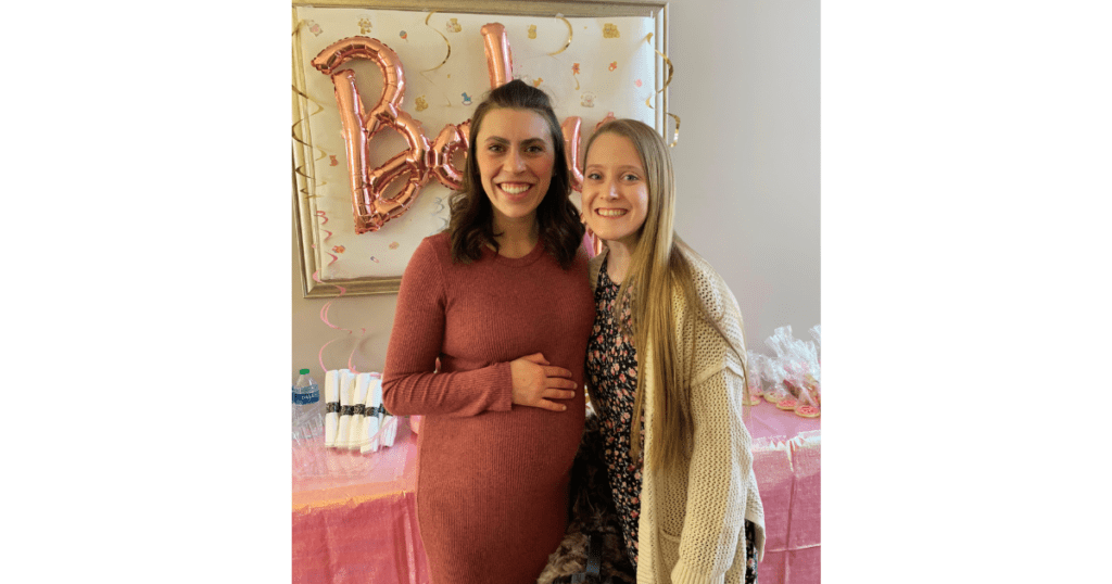 Pink baby sign behind  two women