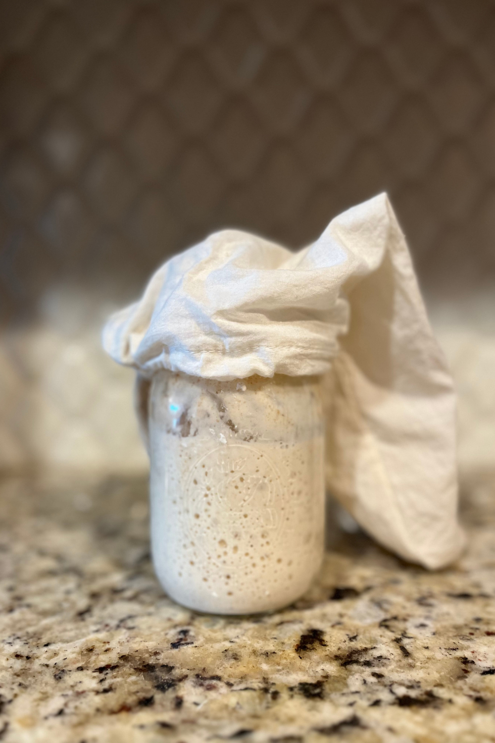 Sourdough starter in a Ball jar with a cheesecloth over the top.