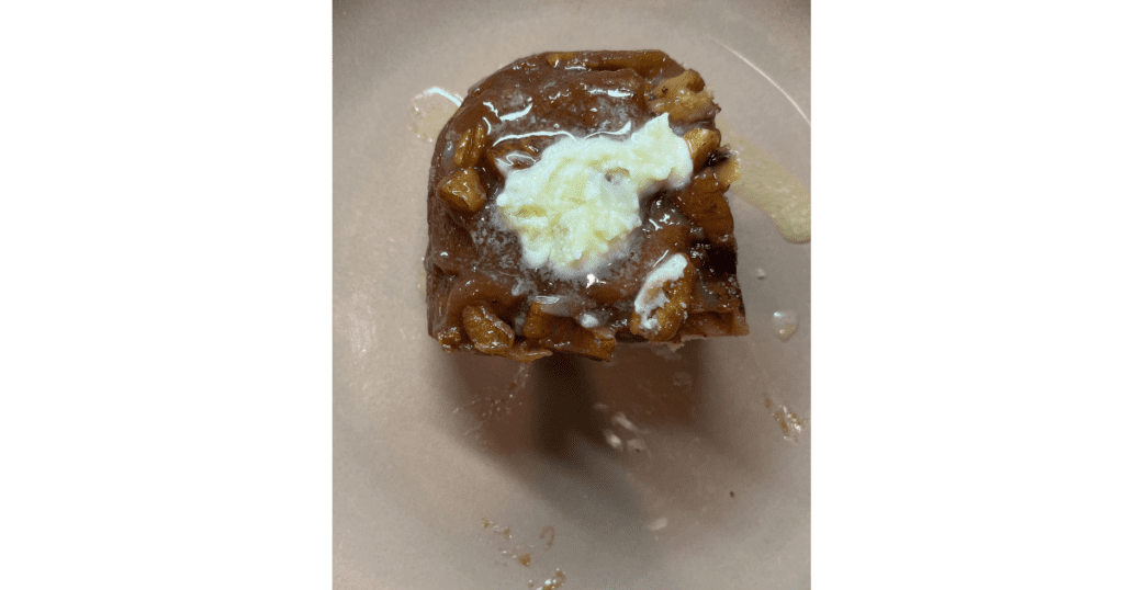 Sticky buns with pecans and butter on top. Brown background.