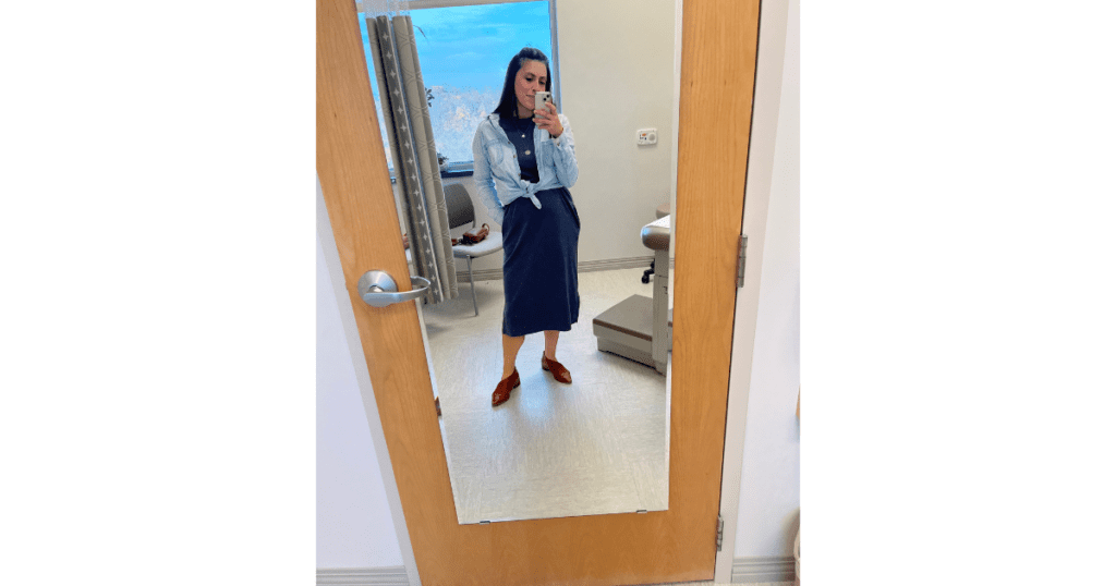 Woman taking photo at doctors office in blue dress and blue shirt.