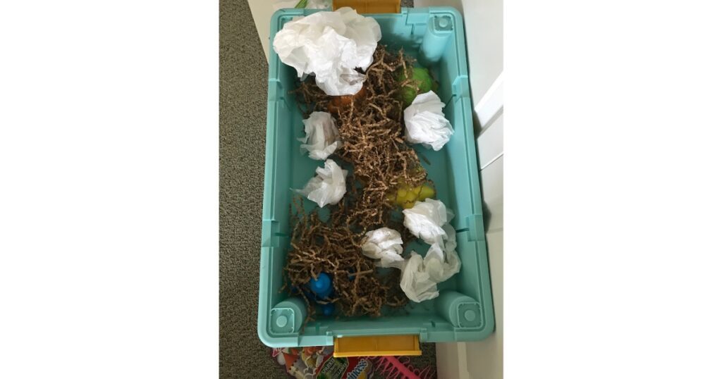 Sensory Activity with gift bags, paper shreds and toys in a sensory table.