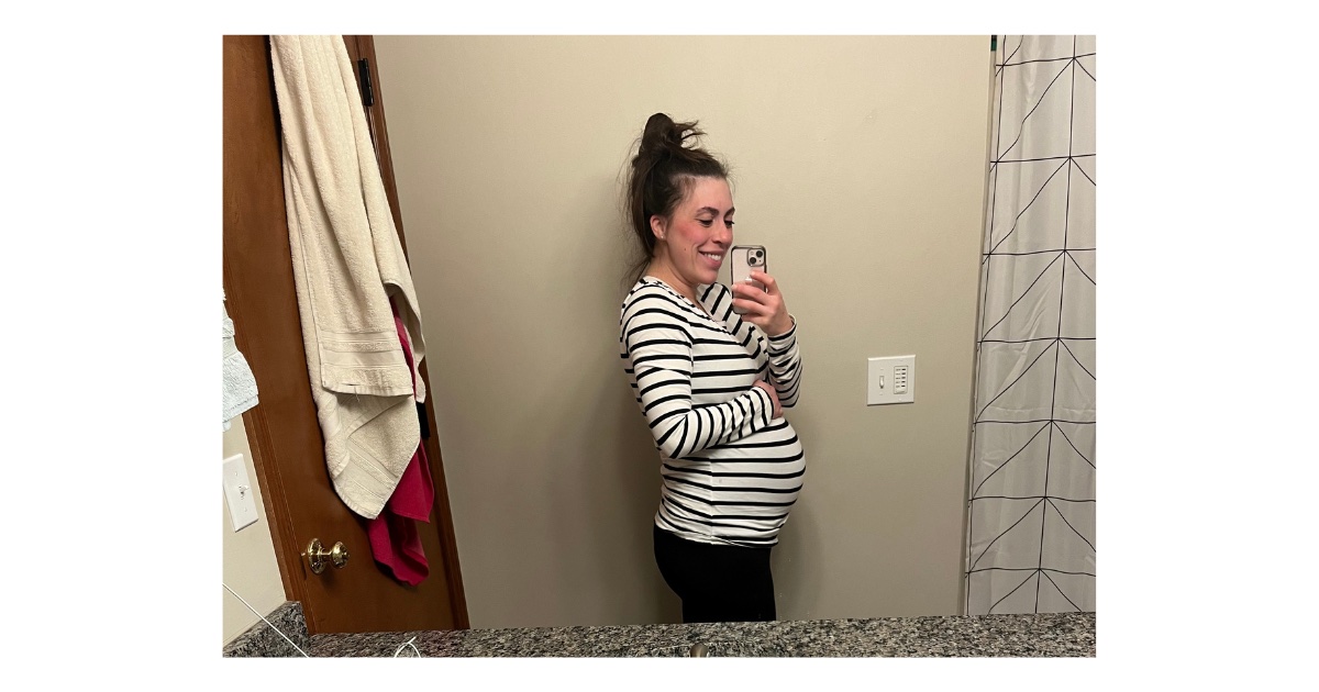 Picture of girl with brown hair and black and white stripped shirt. Towels hanging on door.