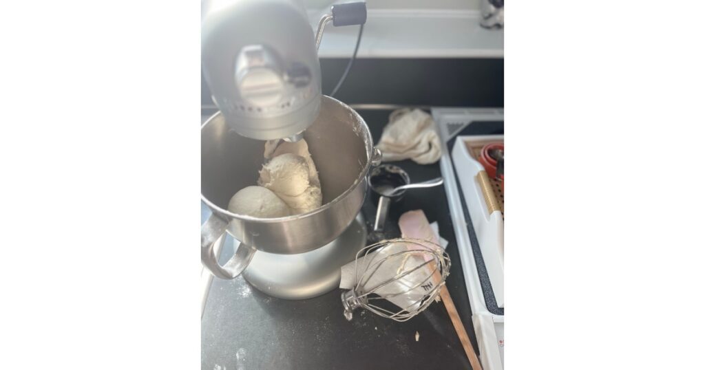 Kitchenaid stand mixer with bagel dough in mixing bowl.