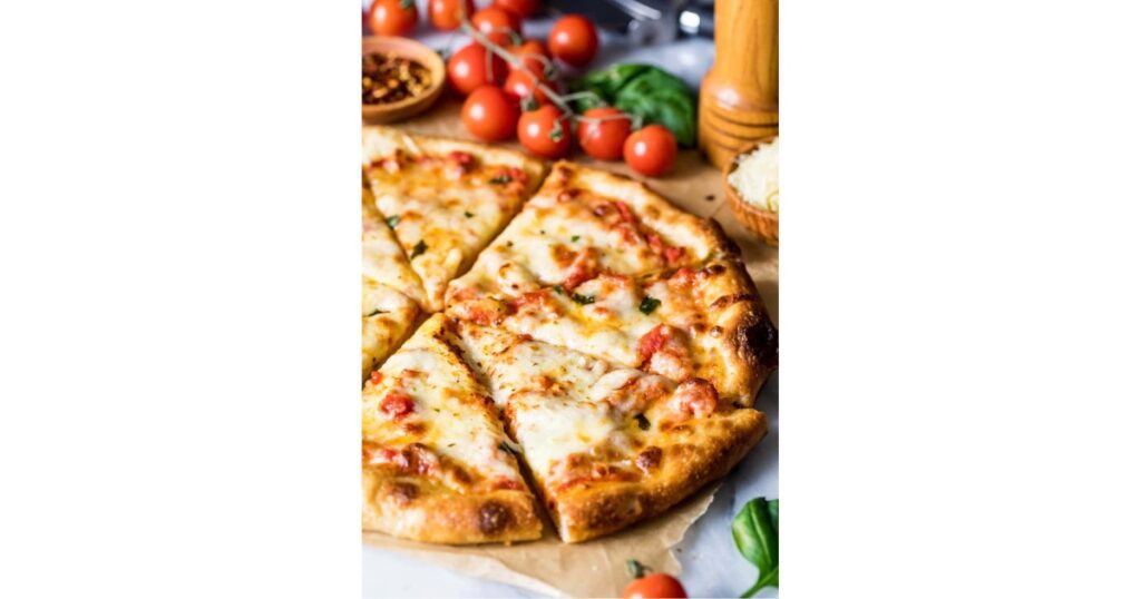 Sourdough cheese pizza with cherry tomatoes and basil in corner.