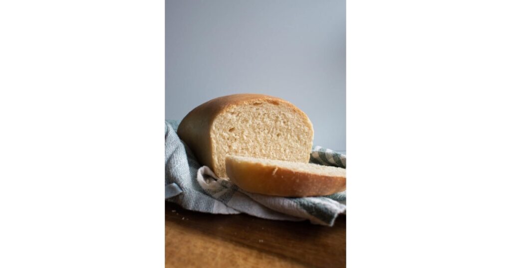 Sourdough bread with a slice cut out of it on top of a blue and white kitchen towel.