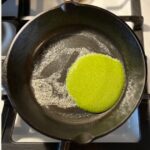 Green pancake on a cast iron skillet with butter