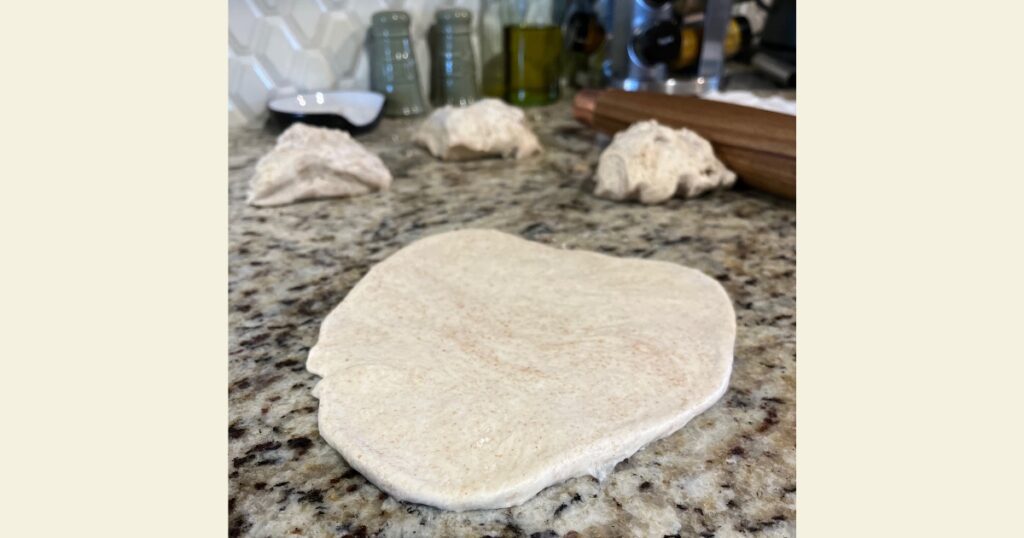 Sourdough pizza crust - 1 flattened, 3 balls behind it