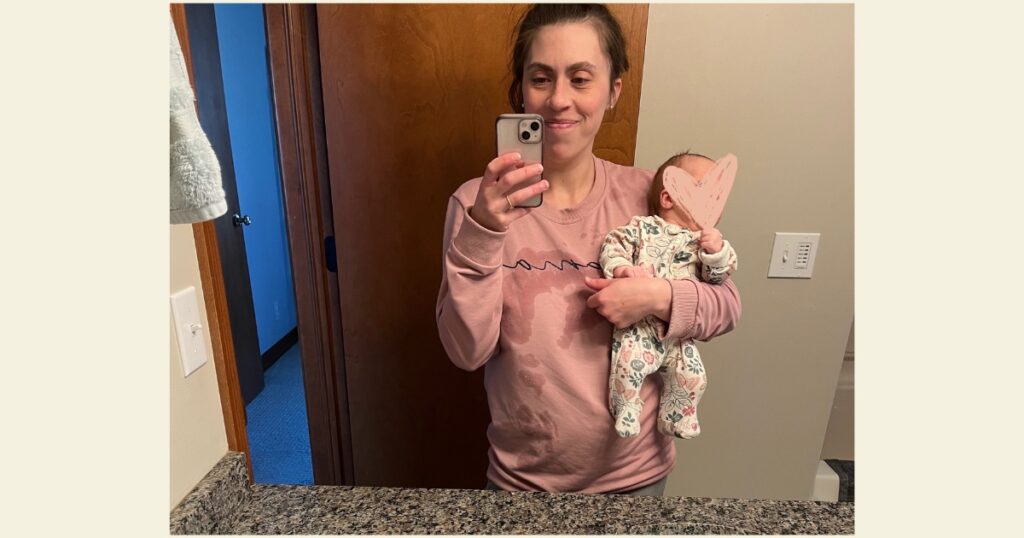 Mom in pink mama sweatshirt with newborn and spit up