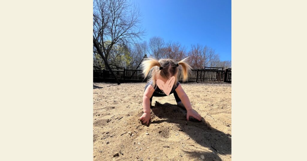 Toddler at park with two pigtails. Playing in sand