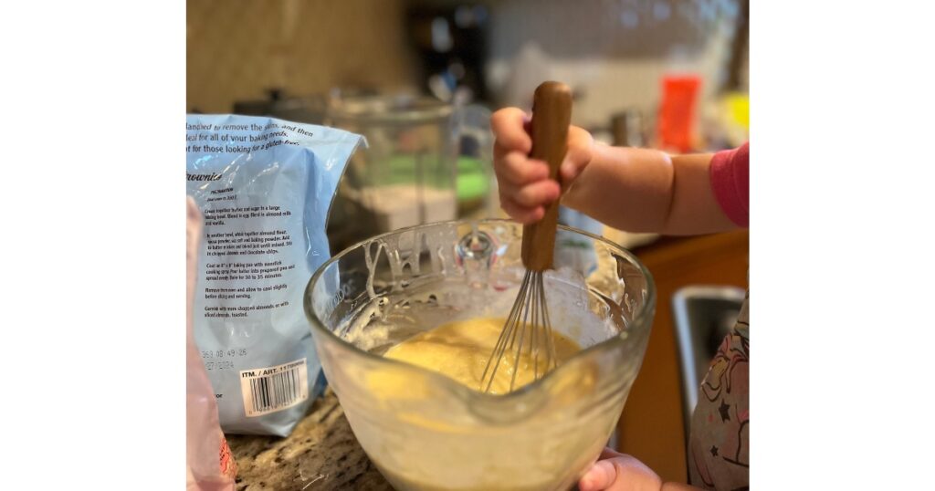 toddler mixing batter in a large bowl.