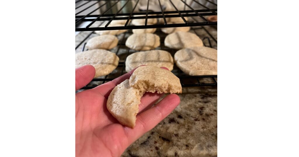 sourdough sugar cookie split in half in front of cookies in back