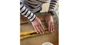 pumpkin cookie dough with reusable chop sticks on top. hand pressing down in middle to make the dough