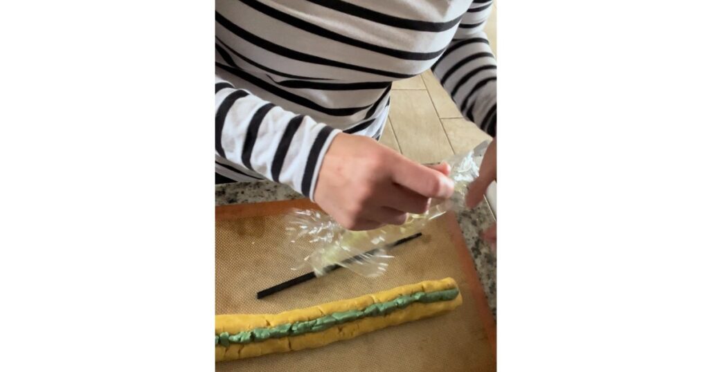 pumpkin cookie dough with plastic wrap above it