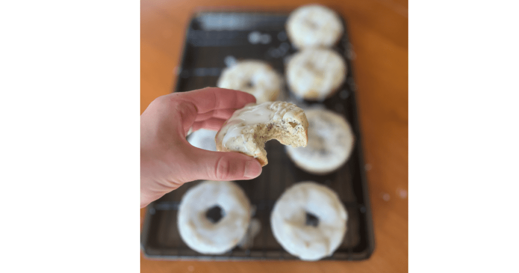 bite out of donut in front of tray of donuts