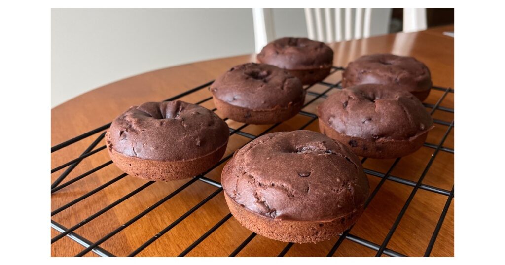 six sourdough chocolate donuts on a cooling rack