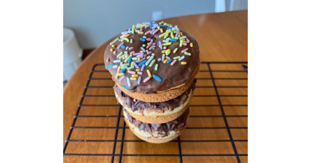 three vanilla sourdough donuts stacked on a cooling rack