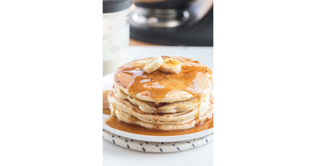 stack of pancakes with maple syrup and bananas on top