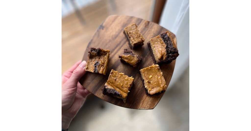 slices of pumpkin cheesecake sourdough brownies on a wooden cutting board