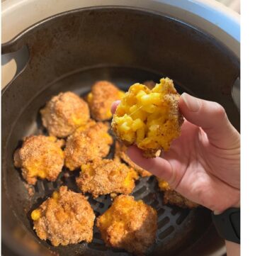 hand holding mac and cheese bite over mac and cheese bites in air fryer