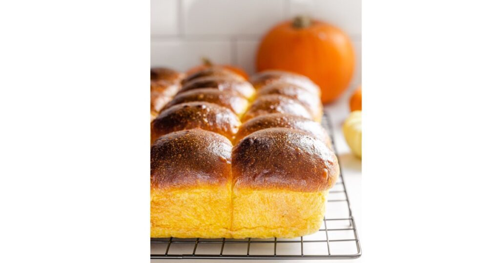 orange dinner rolls on a cooling rack