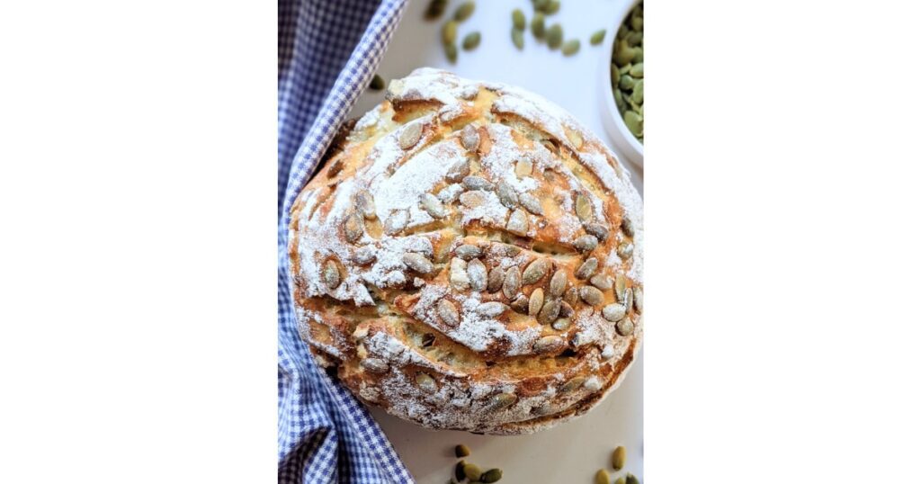 sourdough loaf with flour and pumpkin seeds on top