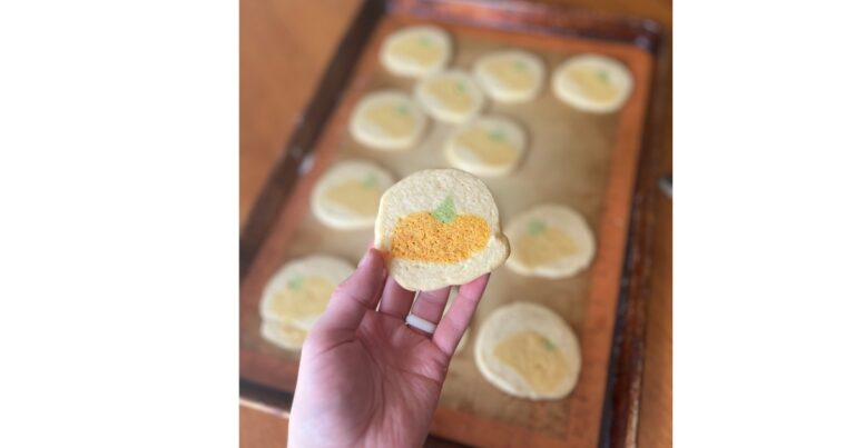 sugar cookies with pumpkin design on a baking sheet