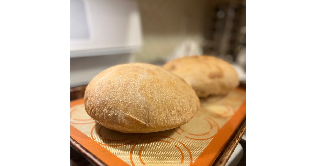 two loaves of sourdough bread on a sheet pan.