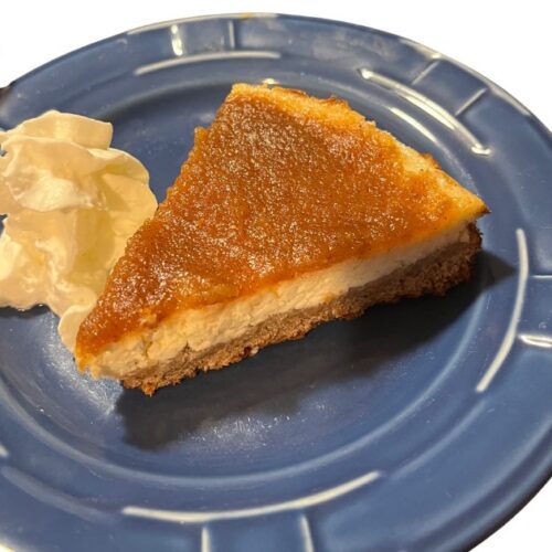 apple butter cheesecake with whipped cream and on a blue plate