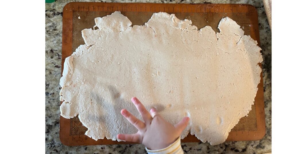 salt dough ornament on sheet tray with finger poking it