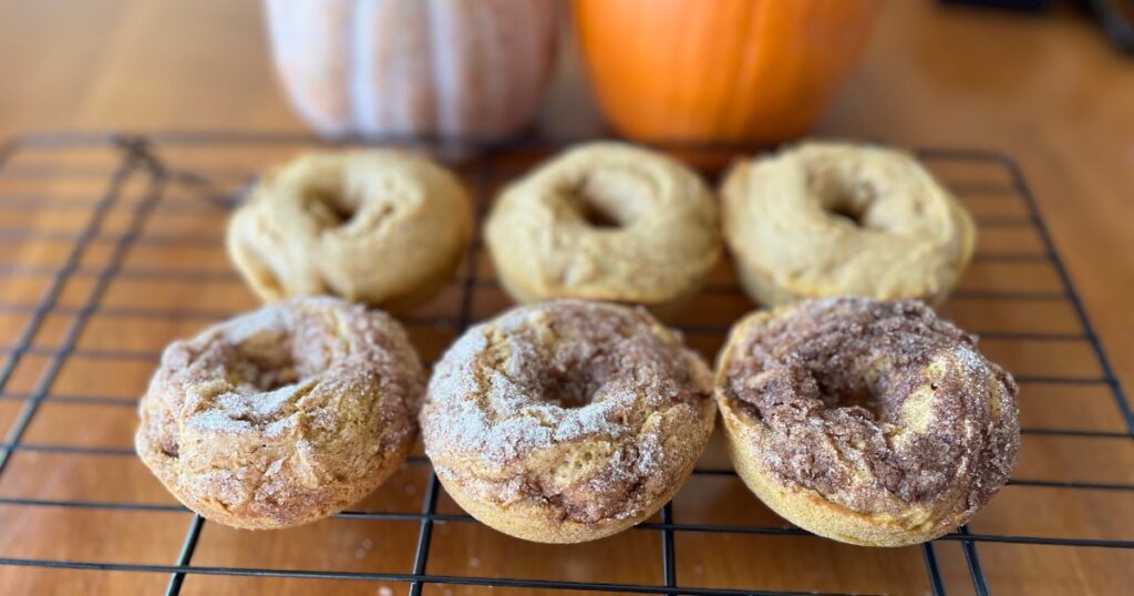 pumpkin donuts on cooling rack and pumpkins in back