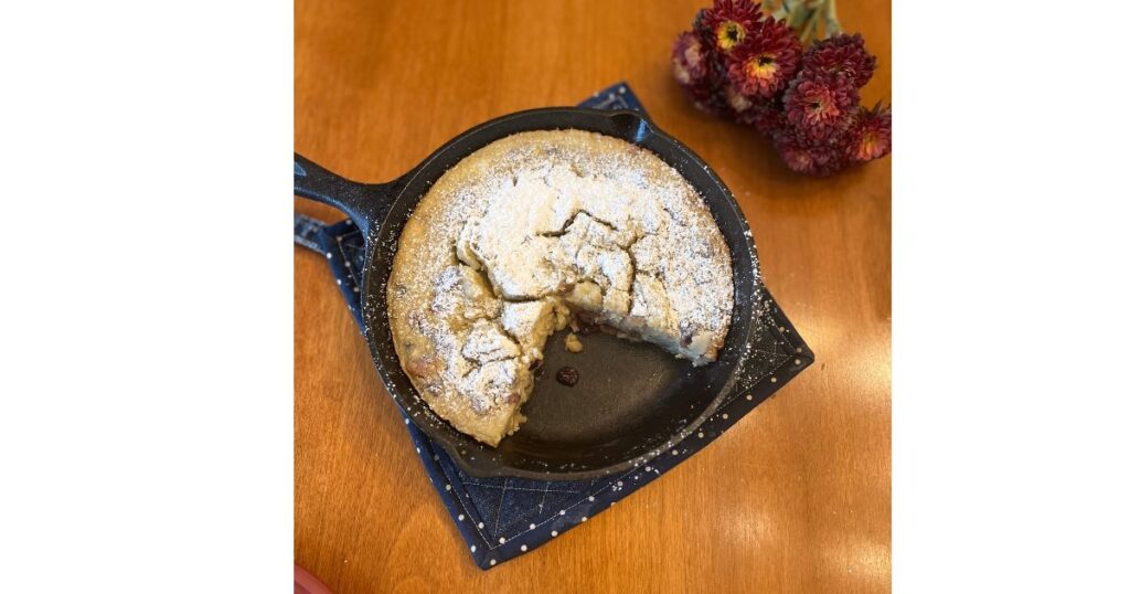 slice of cranberry walnut sourdough dutch baby with flowers behind