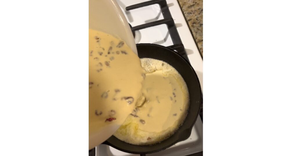 batter with cranberries poured into a cast iron skillet