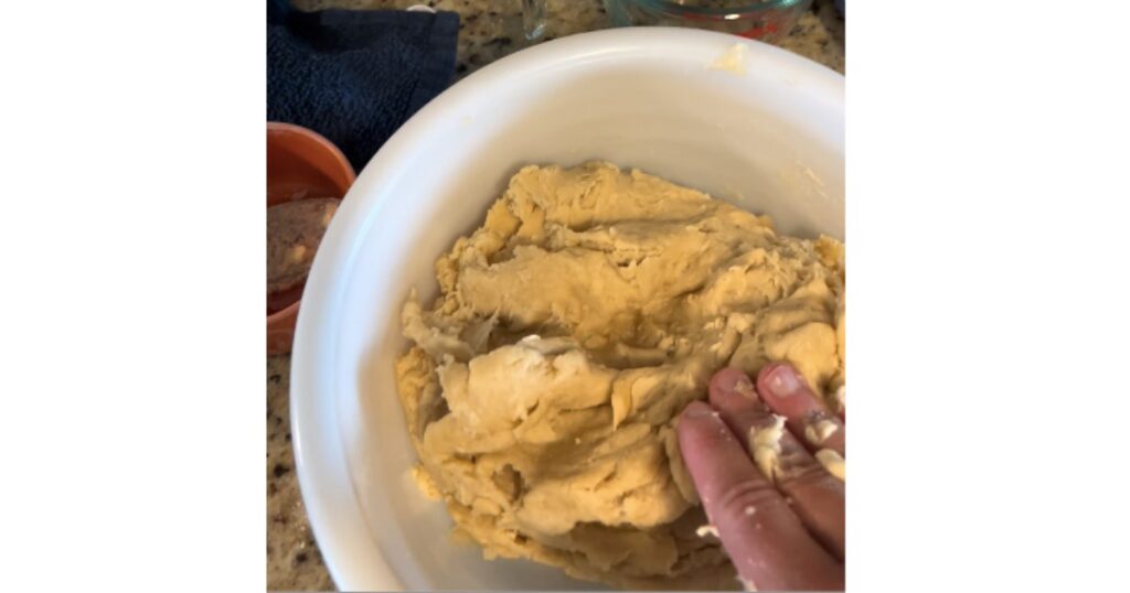 sourdough cinnamon roll dough in white bowl with hand pressing down